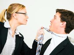 This is a photo of a woman gripping a man by his tie. It appears that she is the powerful one in the photo.