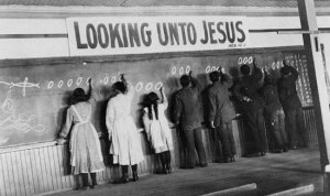 A group of Aboriginal students writing on a blackboard at a residential school. Residential schools were largely run by churches where students were students learned religion and were taught trades.